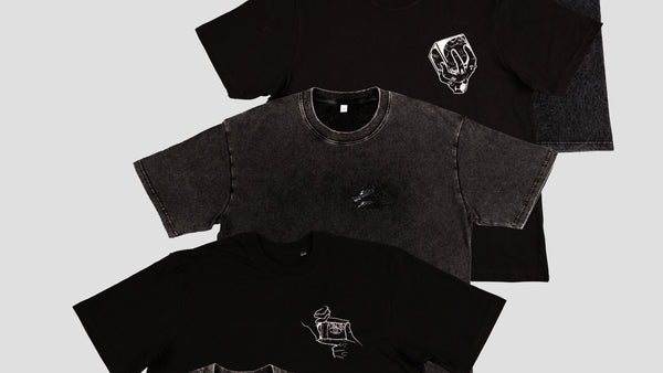 Black t-shirts with embroidered logos on a light gray background